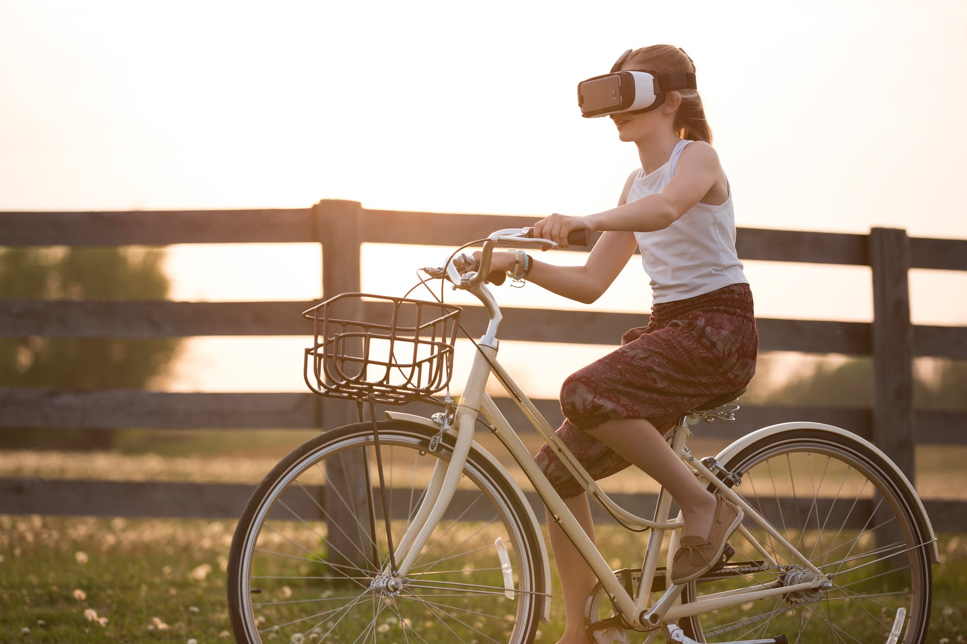 girl wearing vr box driving bicycle during golden hour