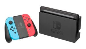 Nintendo Switch console in its dock next to red and blue Joy-Con controllers in a grip