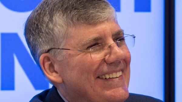 Author Rick Riordan smiling, wearing glasses and a dark jacket
