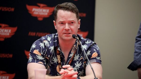 Author Robert Jackson Bennett speaking into a microphone at a convention panel