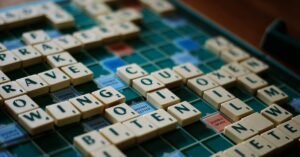 Wooden letter tiles spelling words across a Scrabble board